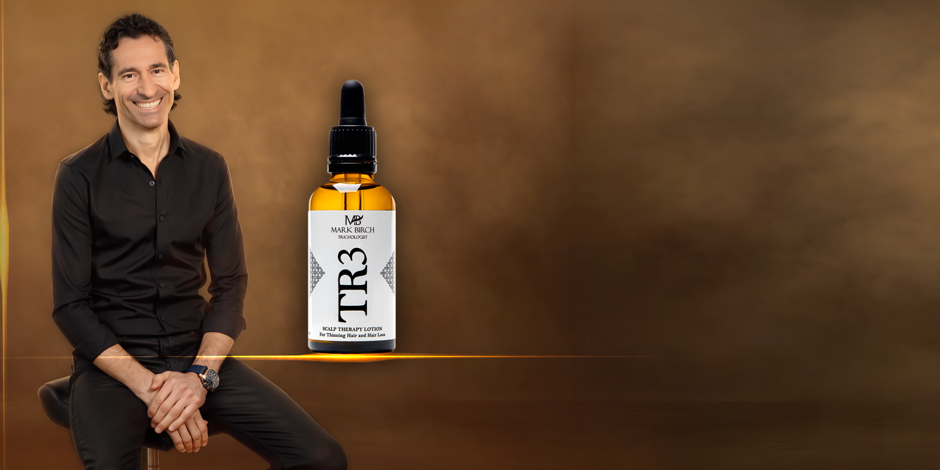 A man in a black shirt sits on a stool against a warm brown background, next to a bottle of TR3 hair serum.